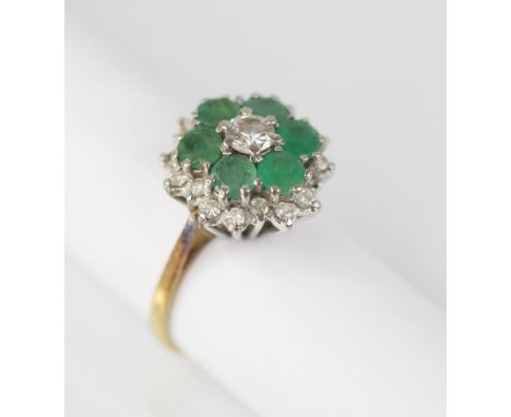 An emerald and diamond floral cluster ring, the central round brilliant cut diamond with a 0.35 carat spread, with a surround