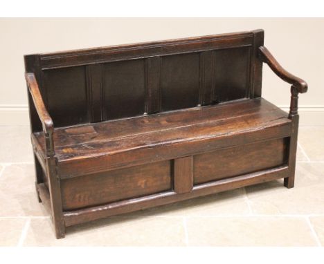 A 17th century and later oak box settle, of cottage proportions, the four panel back extending to down swept arms upon ring t