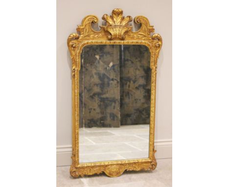 An early 18th century style giltwood and gesso wall mirror, late 19th/early 20th century, the scrolled pediment centred with 