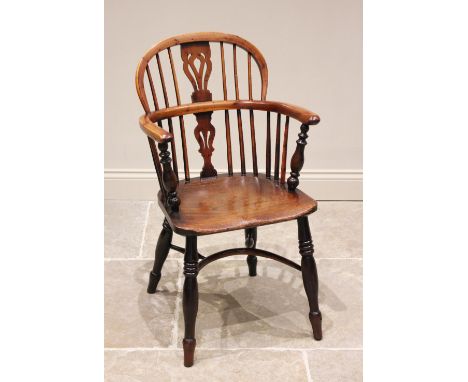 An early 19th century ash, elm and yew Windsor elbow chair, the arched back with a central pierced splat over the elm saddle 