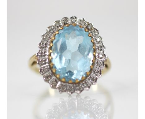 A blue topaz and diamond 9ct gold cluster ring, the oval mixed cut topaz measuring 14mm x 9mm, set to a white gold illusion b