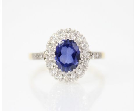 A synthetic sapphire and diamond 18ct gold ring, the central oval mixed cut tanzanite measuring 8mm x 6mm, with a surround of