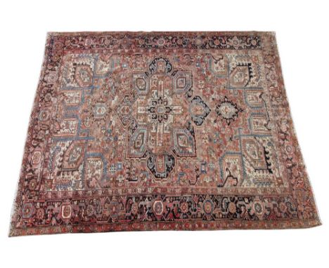 A hand knotted Caucasian village carpet, in red, brown and blue colourways, the central angular medallion enclosed by conform