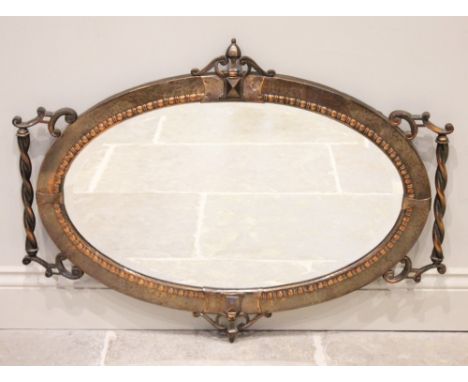 An Arts &amp; Crafts planished copper oval wall mirror, early 20th century, the bevelled mirrored plate enclosed by beaded de