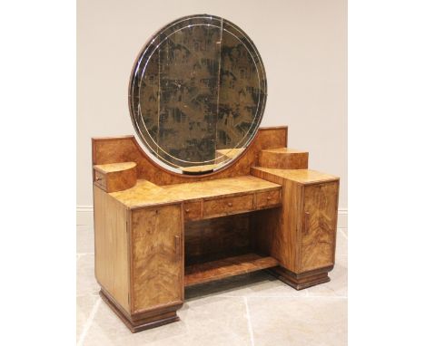 An Art Deco figured walnut dressing table of odeonesque design, with a circular mirror over a pair of quadrant shaped swing d