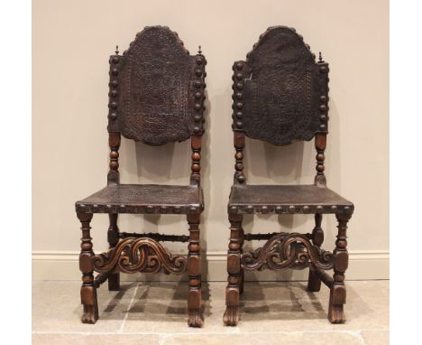 A pair of 17th century and later walnut hall chairs, each with an arched and embossed leather back and seat, applied with lar