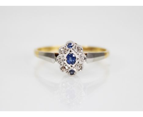 An early 20th century sapphire and diamond 18ct gold and platinum ring, designed as a central oval mixed cut sapphire 2.6mm x