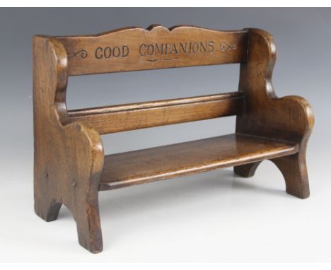 A novelty oak book trough, 20th century, formed as a miniature bench, the shaped top rail inscribed 'Good Companions', 37cm w