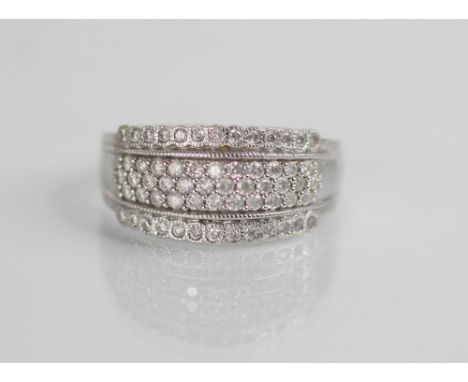 A diamond set 18ct white gold ring, the raised central channel pave set with three rows of round mixed cut diamonds, flanked 