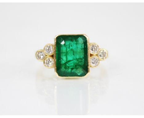 An emerald and diamond 18ct gold ring, the central rectangular step cut emerald with canted corners measuring 11.5mm x 8.6mm 