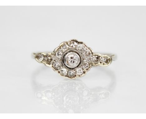 An Edwardian diamond cluster ring, the central old cut diamond approximately 2.30mm diameter, with floral cluster surround an