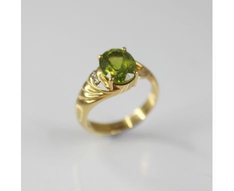 A peridot and diamond 18ct gold ring, the central oval mixed cut peridot measuring 10mm x 8mm, claw set to an 18ct gold asymm
