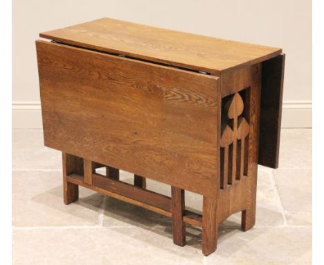 An early 20th century oak drop leaf table in the manner of Liberty, the rectangular top raised upon openwork supports in the 