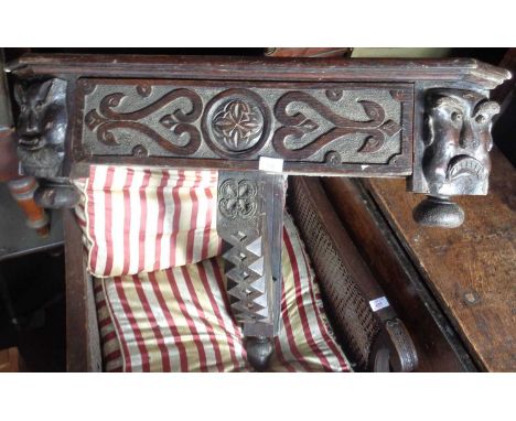 Victorian gothic carved oak corner shelf having bold carving of grotesque masks flanking a single drawer with chip carved sup