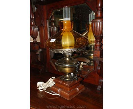 An Oil Lamp converted for electricity with white glass chimney and amber shade on a wooden base.