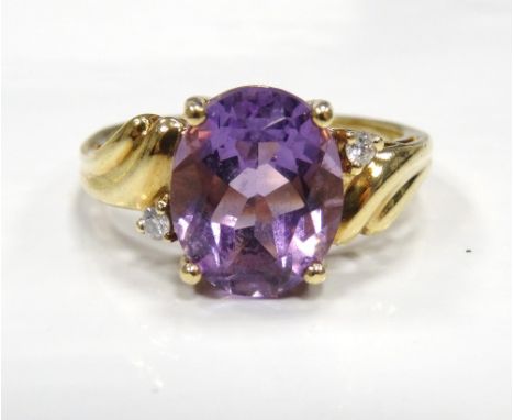 AMETHYST AND DIAMOND DRESS RINGthe large central oval cut amethyst with a diamond to each side, on nine carat gold shank, rin