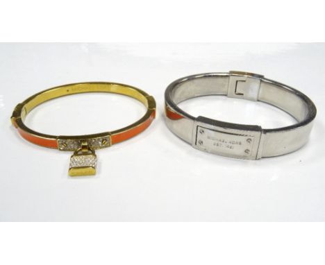 TWO MICHAEL KORS BANGLESone in silver tone with logo panel; the other in gold tone with orange enamel and pave set padlock (2
