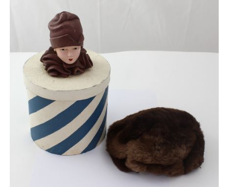 An Art Deco style shop display hat box with ceramic Art Deco head to top and containing a vintage hat.