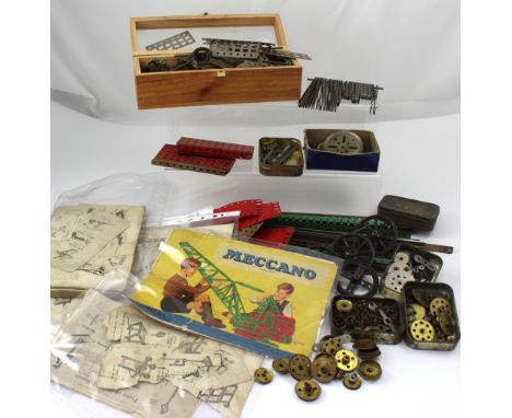 A small collection of vintage Meccano, with brass train wheels and various instruction booklets.
