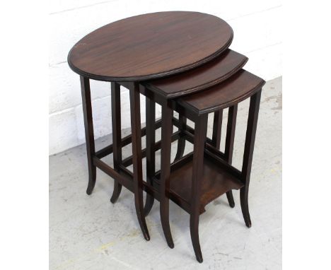 An early-to-mid 20th century nest of three mahogany tables, largest with oval top and smallest with a shelf stretcher, 62 x 5