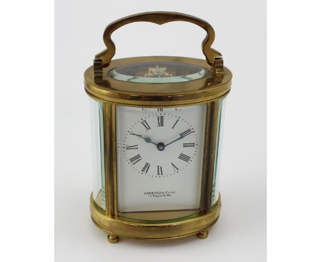 A Garrard & Co Ltd oval brass carriage clock, the dial set with Roman numerals behind glass panels, supported on bun feet, he