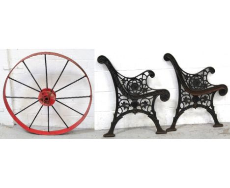 A pair of cast iron bench ends, a large metal spoked steam traction engine wheel, diameter 111.5cm and a manger (3).