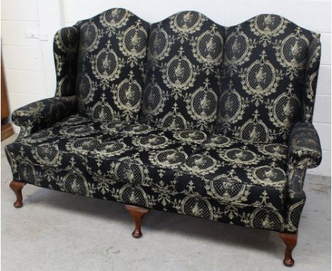 An Edwardian-style three-seat sofa with deep scrolling back to scrolling arms, on squat cabriole supports, upholstered in gol