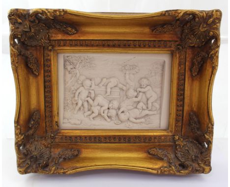 A reconstituted marble plaque of putti playing, in a gilded frame, metal plaque inset verso dated 1882, 11 x 15cm, framed.