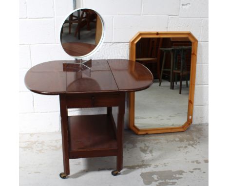 A mid-20th century mahogany drinks cabinet with drop leaves to either side over a shelf, on block supports to castors, a pine