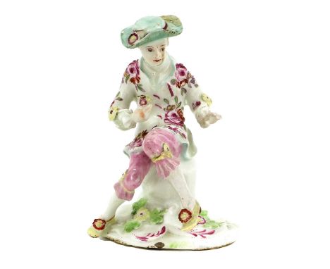 A Derby Porcelain Figure of a Boy, circa 1755, seated on a rock and holding three flowers in one hand, on a pad base moulded 