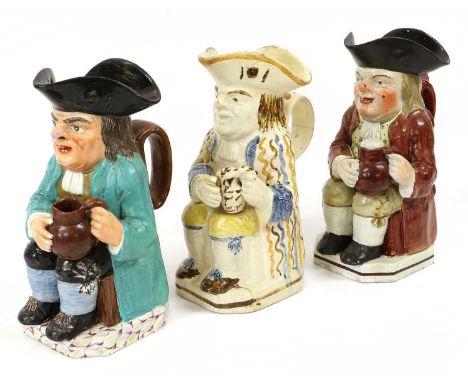 A Pearlware Toby Jug, early 19th century, painted with a turquoise overcoat and holding an empty brown jug, raised on a marbl