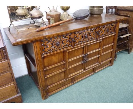 A 20th Century Eastern elm and walnut sideboard.  The base with central pair of doors enclosing a fitted shelf, three deep dr