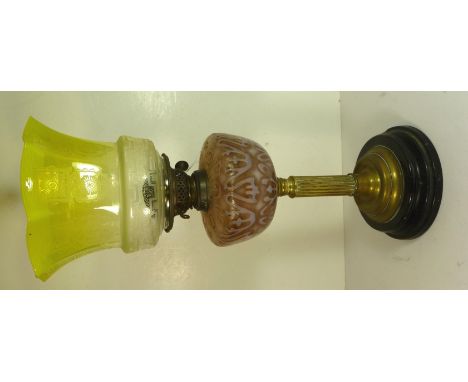 A Victorian oil lamp with light pink coloured reservoir with raised decoration, fluted brass column and on black enamel stepp