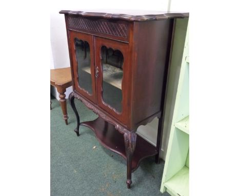 A Victorian mahogany side cabinet.  The pair of glazed doors enclosing a fitted shelf, on carved cabriole legs and with undul