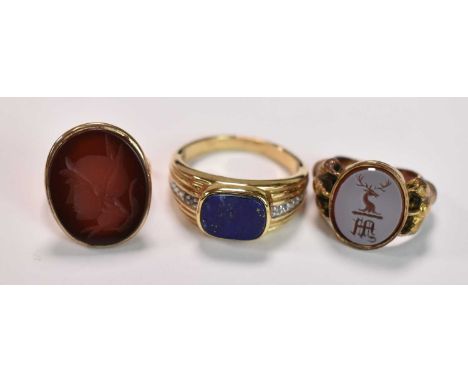 Three yellow metal rings, one set with a carved carnelian, size O, 4.9g approx one with central lapis lazuli panel, size Z 1/