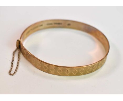 A 9ct yellow gold engraved oval hinged bangle, internal width 60mm, approx 14.7g. 