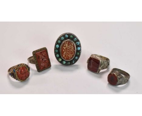 A very large white metal ring centred with a carnelian set with Arabic script within a border of turquoise beads, and four ot