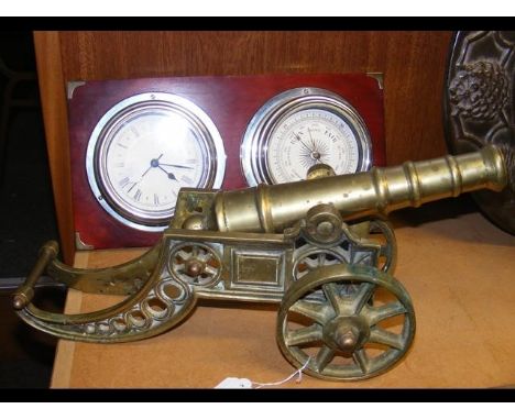 A brass canon together with a mounted clock and barometer 