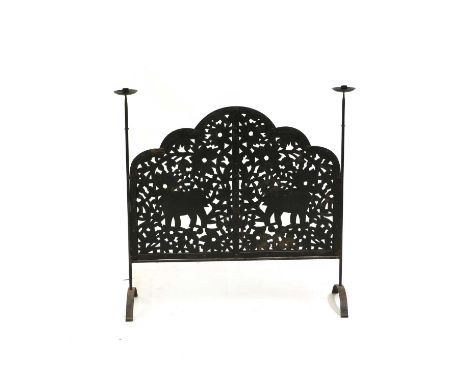 A wrought-iron firescreen, the shaped and pierced panel with flowers and two elephants, flanked with candle branches, 96.5cm 