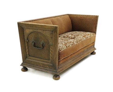 A Continental oak trunk sofa, early 20th century, upholstered in brown wool fabric, with studded edges, the seats with an emb