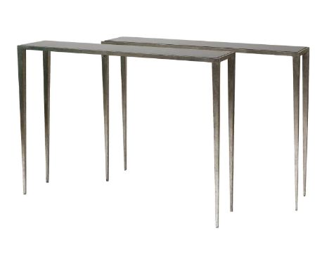 A pair of contemporary moulded aluminium console tables, of rectangular form, each with an inset smoked glass top, raised on 