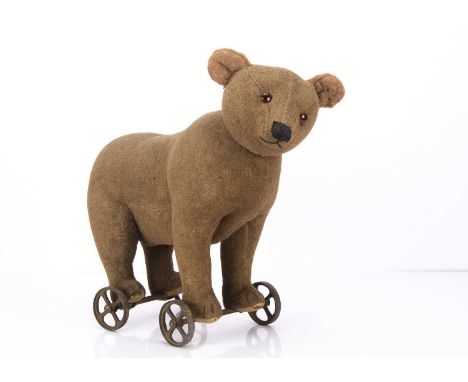 An early Steiff centre-seam bear on wheels 1905-10, of brown burlap plush, replaced orange and black glass eyes, pronounced m