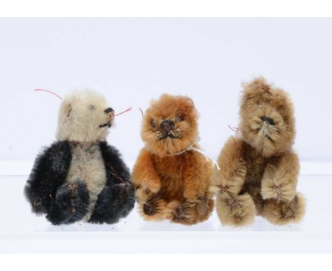 Three post-war Schuco miniature teddy bears, a panda, a cinnamon and a light brown mohair bear, all  with black pin eyes, bla