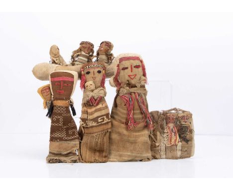 Peruvian Chancay cloth burial dolls, three figures holding babies —10in. (25cm.) high, a canoe with three figures and three l