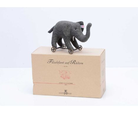 A Steiff Club limited edition felt elephant of wheels,  987 for the year 2004, grey felt on cast iron wheels, in original  bo