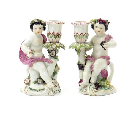 A pair of Derby candlestick figures, c.1760-65, emblematic of Spring and Autumn, each modelled as a putto seated on a low stu