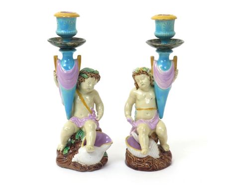 A rare pair of Majolica candlesticks, 2nd half 19th century, possibly George Jones, each modelled as a putto seated on a rock