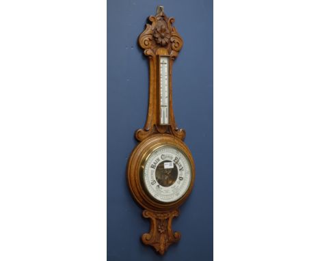 Early 20th century heavily carved golden oak case aneroid barometer with mercury thermometer, H90cm   Condition Report   Clic