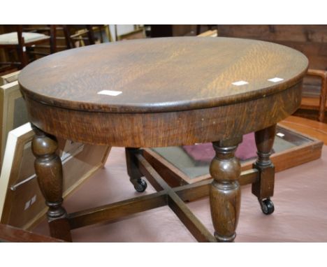 An oak occasional table, circular top, deep frieze, turned legs, X-frame stretchers, ceramic casters.