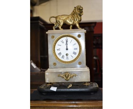 A marble mantel clock, enamelled dial, Roman numerals, gilt lion pediment.